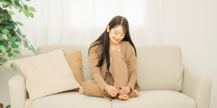 ソファで足の爪を切る女性